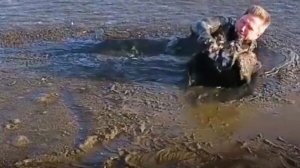 Man crawls through treacherous black mud after noticing helpless trapped animal